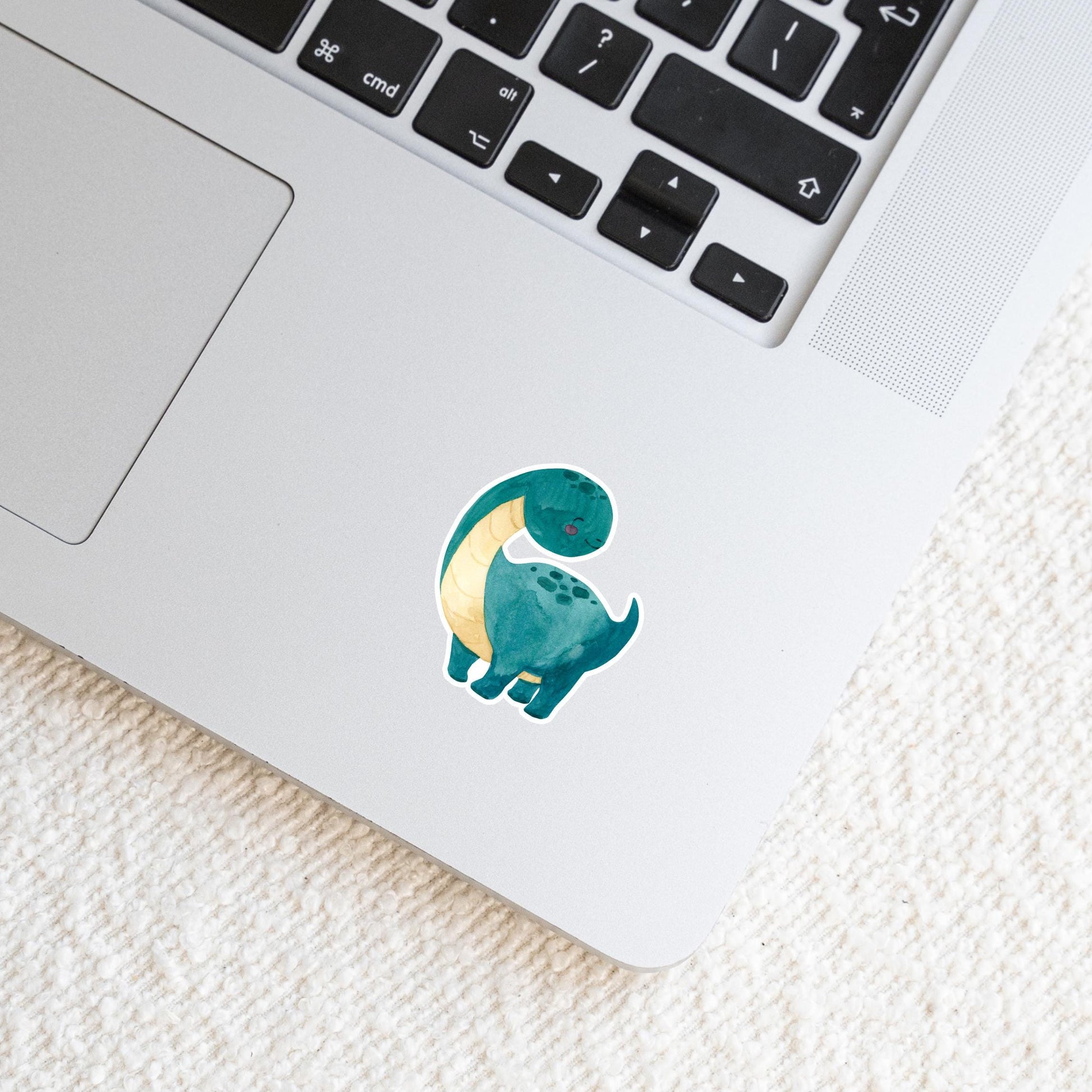 Laptop mit einem Sticker Dinosaurier dunkelgrün, handgemalter Dino-Sticker auf der Oberfläche, ideal für personalisierte Dekorationen und langlebig.