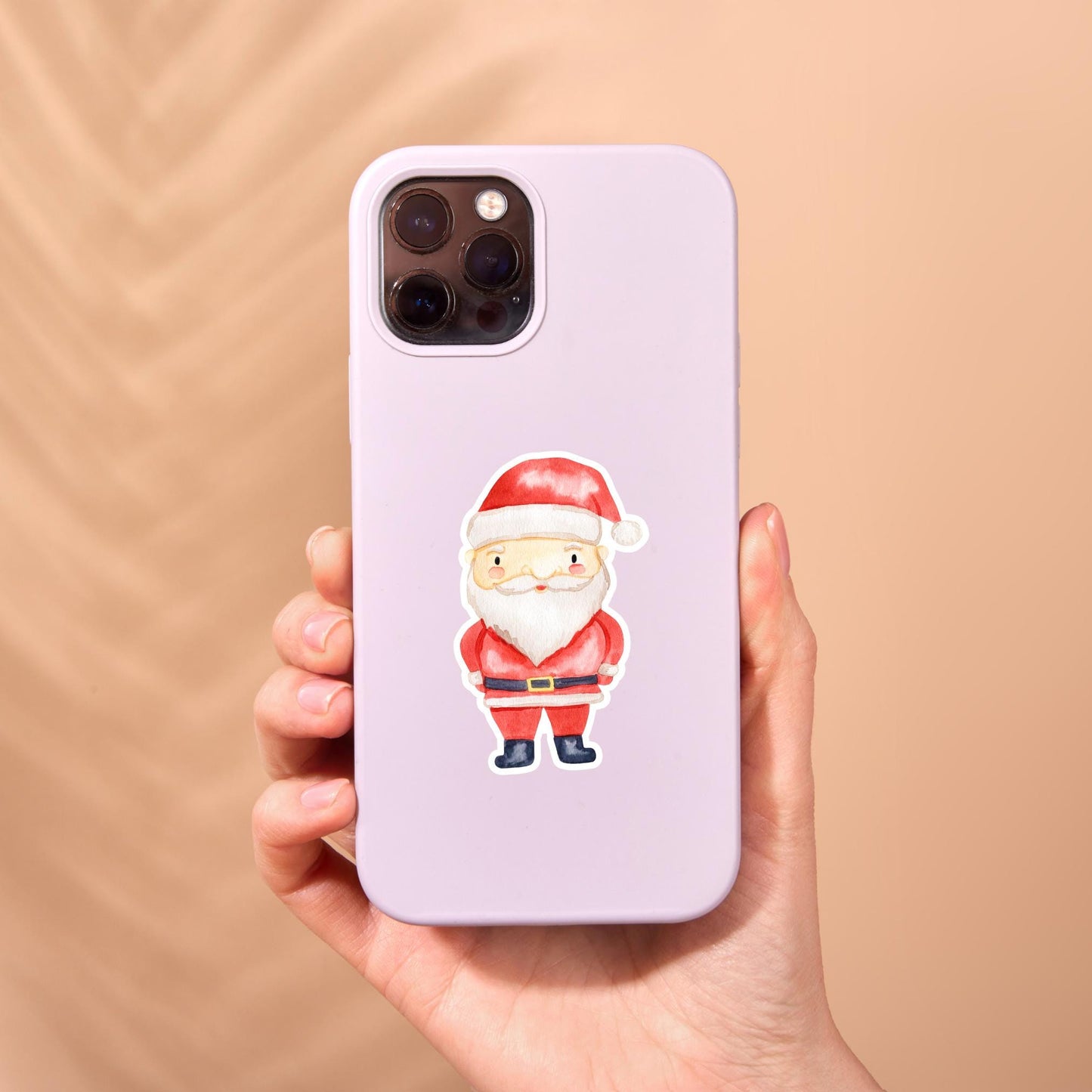 Eine Hand hält ein iPhone mit einem Sticker Weihnachtsmann, einem handgefertigten, spritzfesten Vinyl-Aufkleber, ideal für Handyhüllen oder Dekorationen.