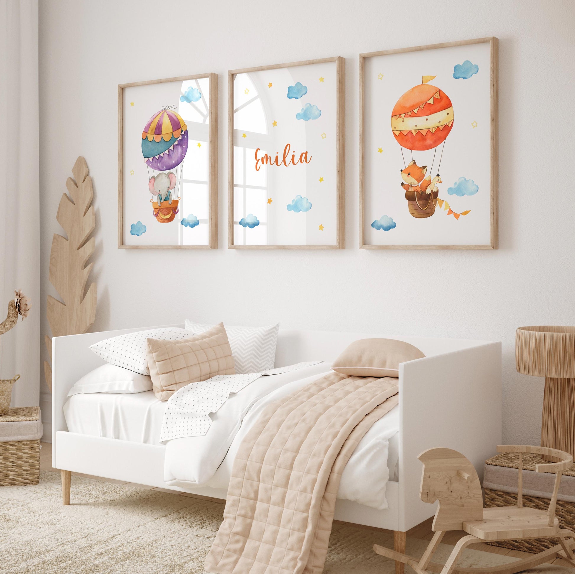 Namensposter personalisiert im 3er Set: Elefant und Fuchs im Heißluftballon, begleitet von Wolken und Sternen, über einem Kinderbett in neutralen Tönen.