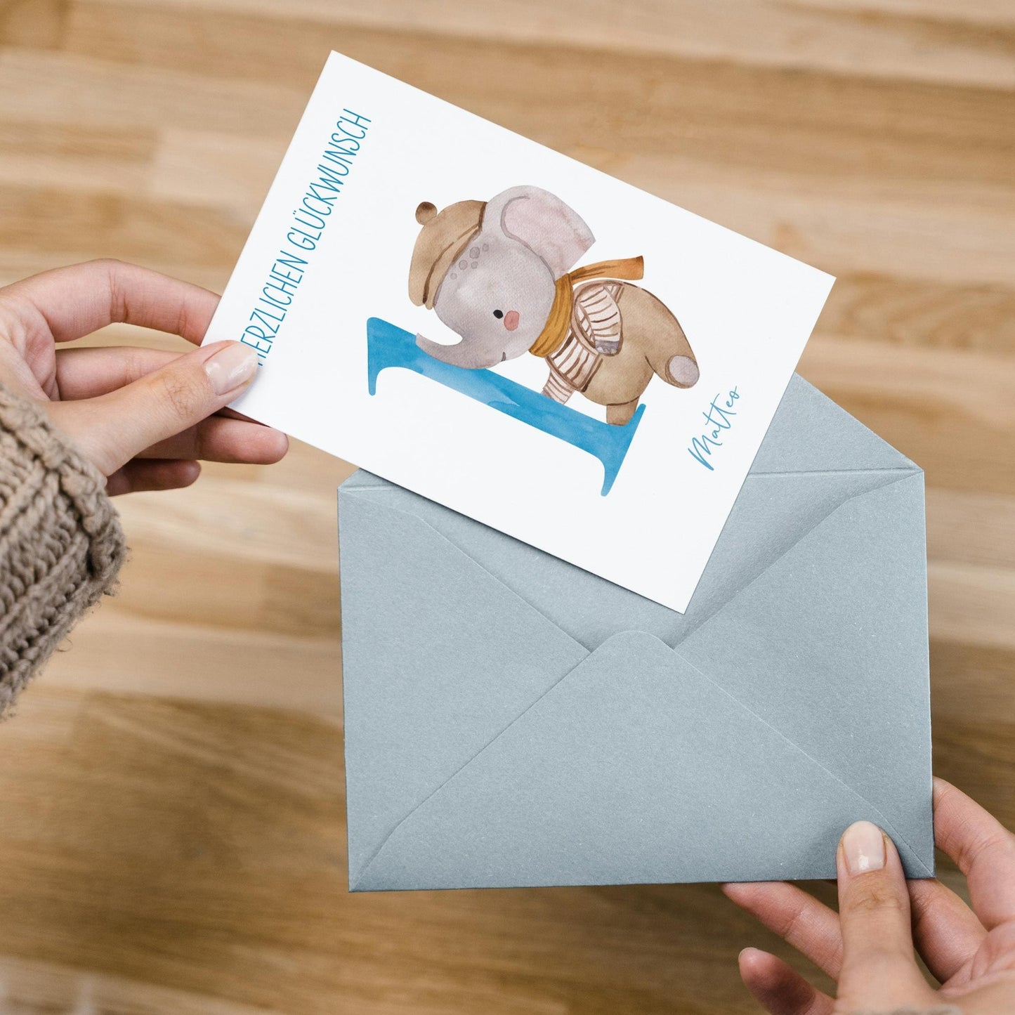 Hände halten einen Umschlag mit der Personalisierte Geburtstagskarte Elefant A6, die einen Elefanten auf einer „1“ zeigt, personalisierbar mit Namen.