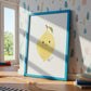 Namensposter Zitrone A3 & A4 mit lächelnder Zitrone im blauen Rahmen, gestützt an der Wand, neben Spielzeugzug und Kinderbüchern, ideal für Kinderzimmerdekoration.