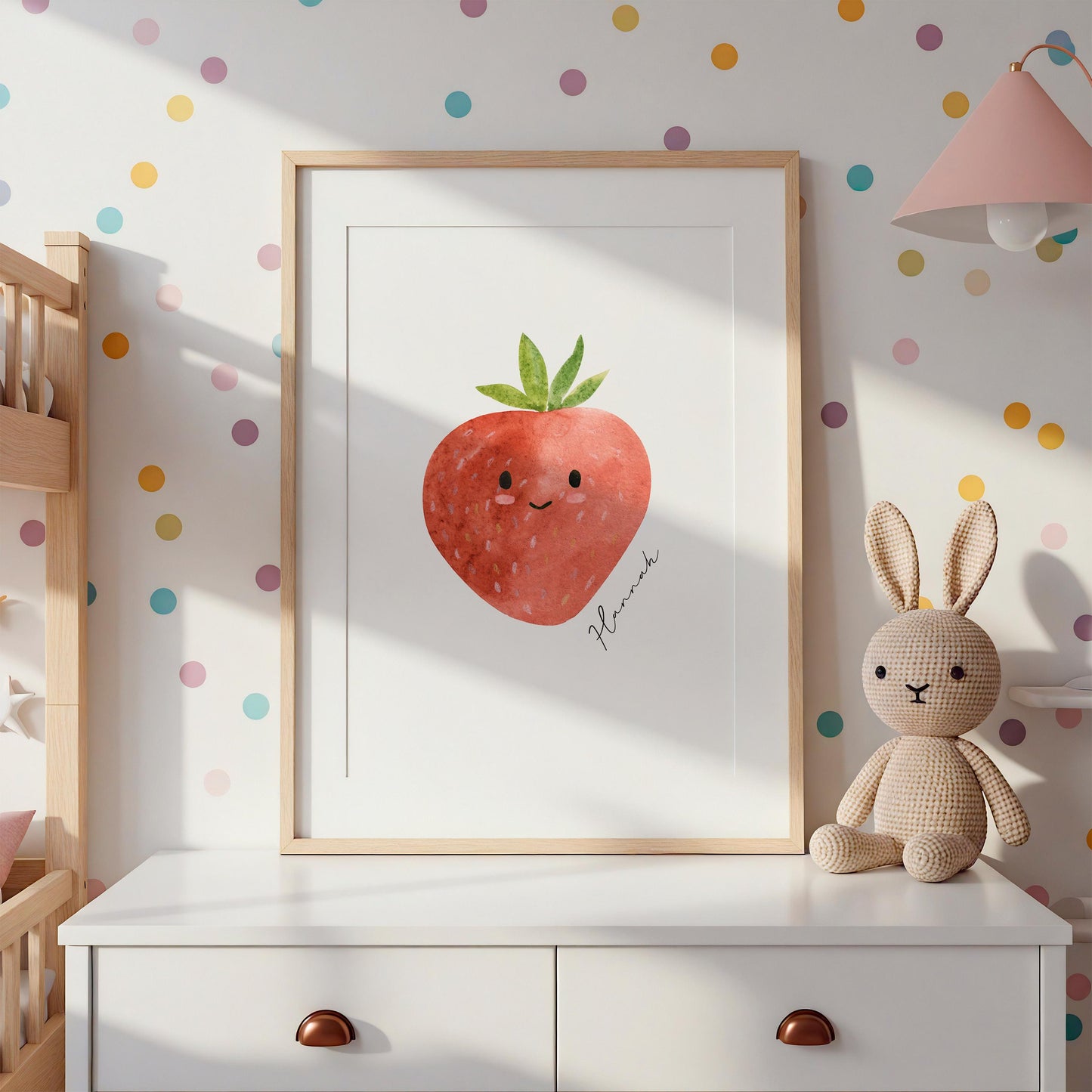 Namensposter Erdbeere A3 & A4 in Holzrahmen, zeigt lächelnde Erdbeere. Personalisierbar, hochwertiges Naturpapier. Neben ihm eine gehäkelte Häschenpuppe.