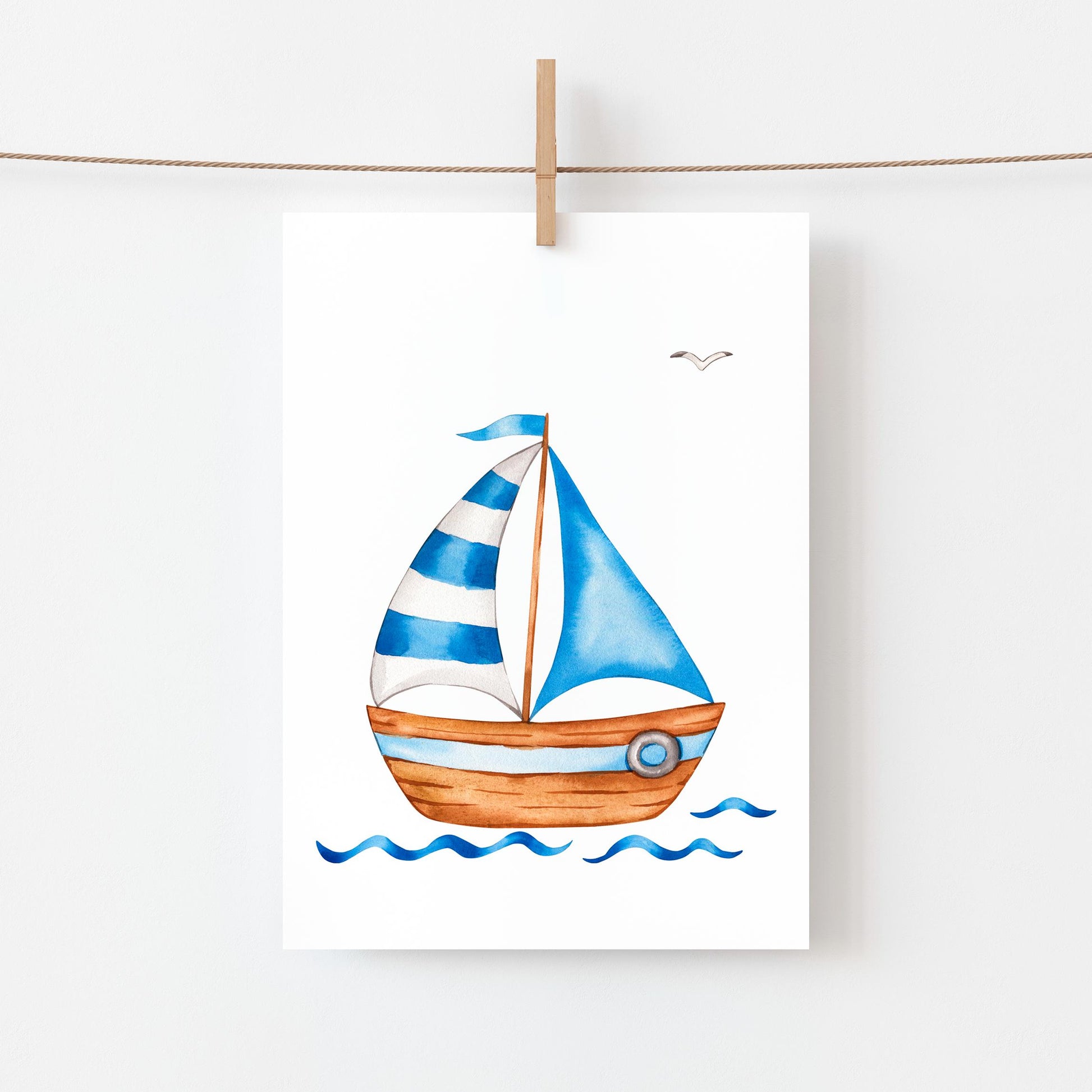 Postkarte Segelboot A6 zeigt ein stilisiertes Aquarell eines Segelboots mit zwei blauen Segeln auf sanften Wellen, aufgehängt an einer Holzklammer.