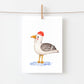 Postkarte Möwe A6 zeigt eine Möwe im Aquarellstil auf Naturpapier, mit gelbem Schnabel, grauen Flügeln und roter Mütze, aufgehängt an einer Kordel.