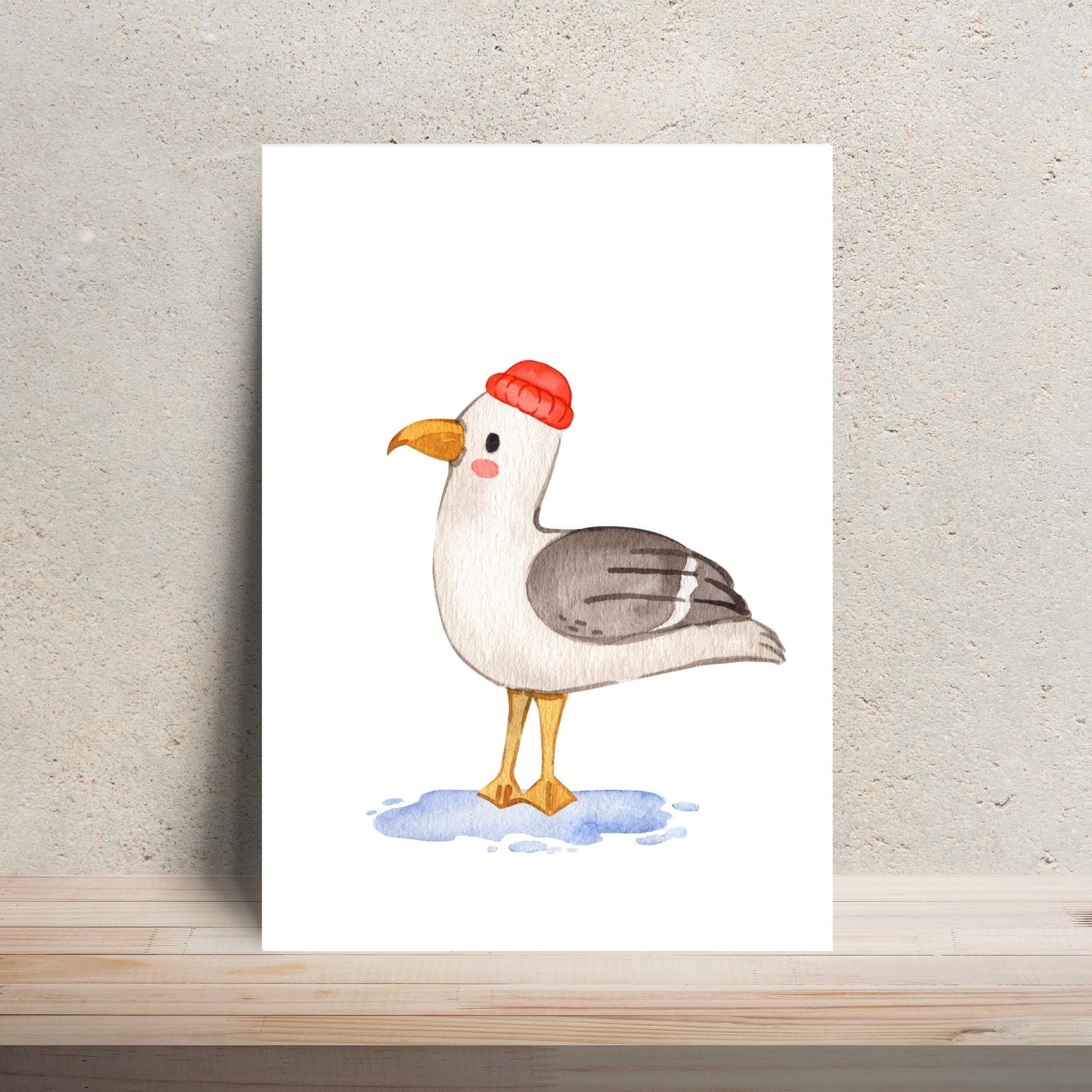 Postkarte Möwe A6 mit Aquarell-Möwen-Illustration in roter Strickmütze, stehend im Wasser. Gedruckt auf hochwertigem, mattem Naturpapier für langlebige Farbbrillanz.